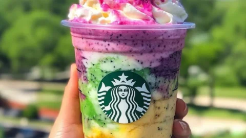 A colorful Dragon Frappuccino with vibrant green and purple hues, topped with whipped cream and sprinkles.